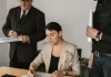 Zespół menedżerów analizuje wydrukowane wykresy i podpisuje dokumenty.