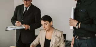 Zespół menedżerów analizuje wydrukowane wykresy i podpisuje dokumenty.